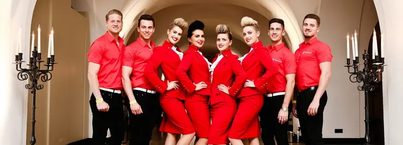 Event staff team of hostesses and hosts in matching red uniforms at a venue entrance