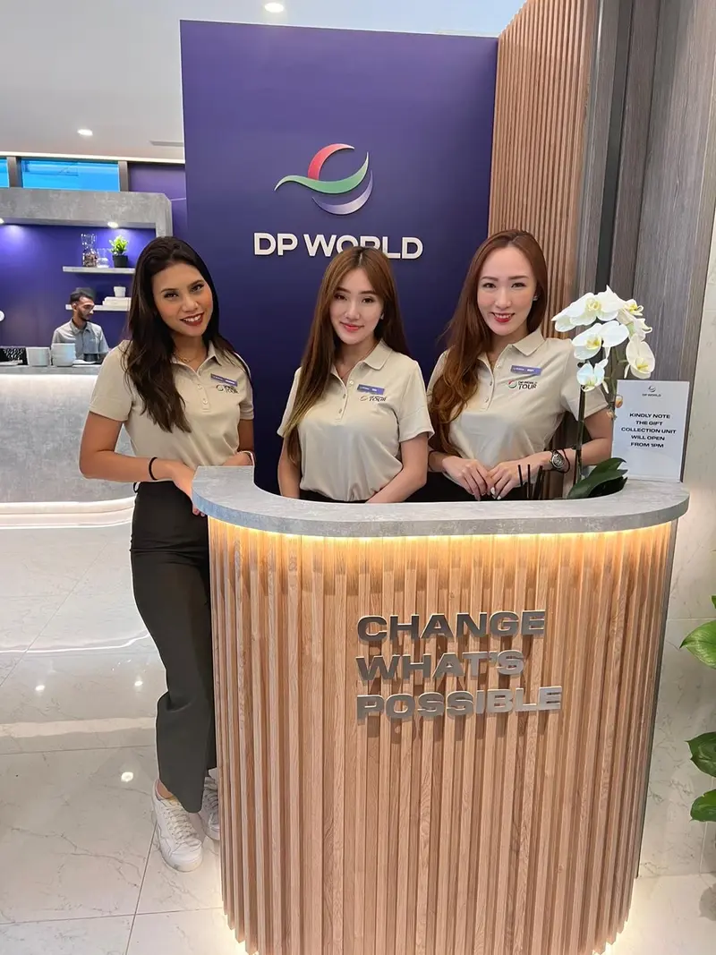 Three hostesses at a wooden welcome desk in a corporate hospitality lounge