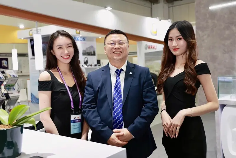 Two booth hostesses with an exhibitor at a trade show stand