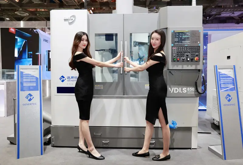 Two exhibition hostesses in black dresses presenting a machining centre on a trade show stand