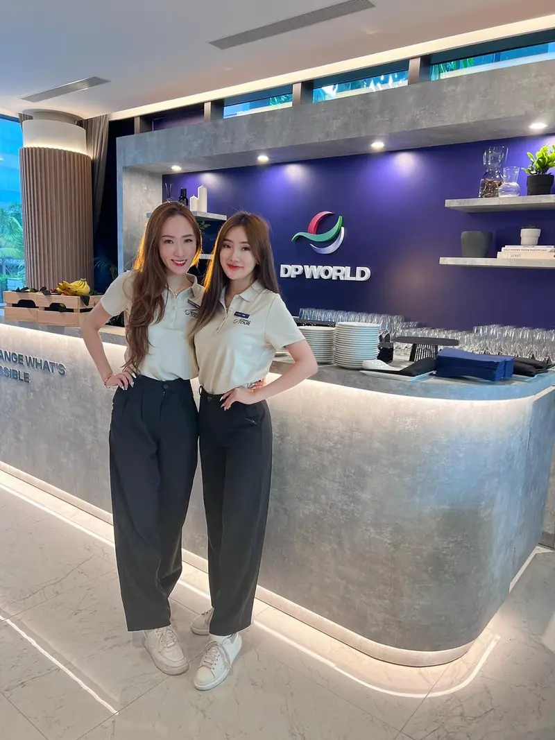 Two hospitality hostesses in uniform polo shirts at a corporate hospitality lounge bar