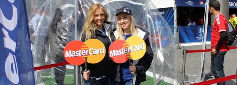 Two promotional staff holding sponsor paddles at a football fan zone