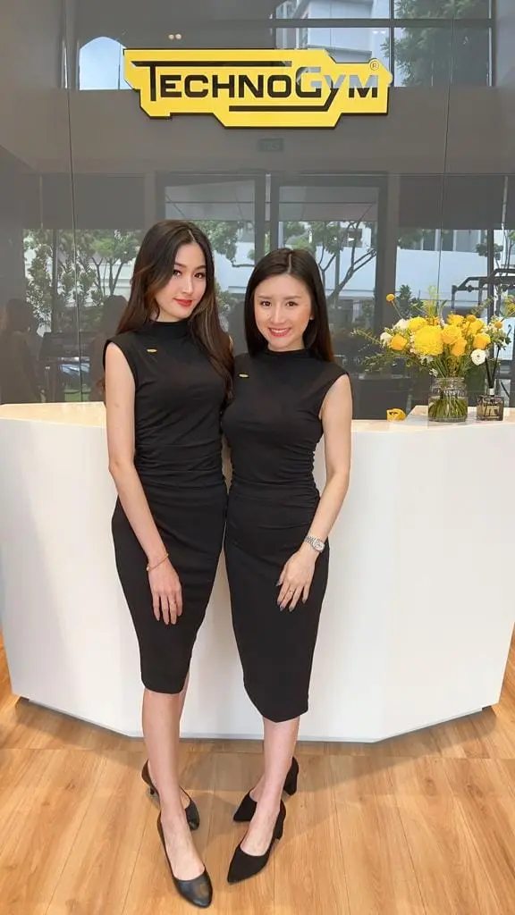 Two reception hostesses in black dresses at a showroom welcome desk