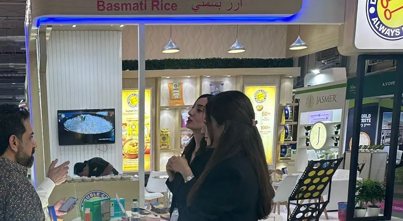 Two stand staff in black talking with a visitor at a food brand stand at a trade show